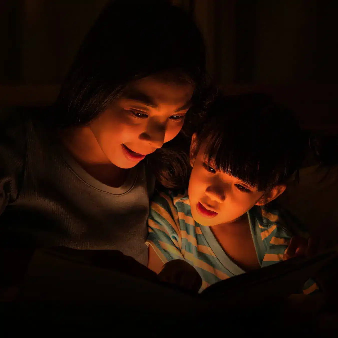 Mother and Daughter reading a book in the dark